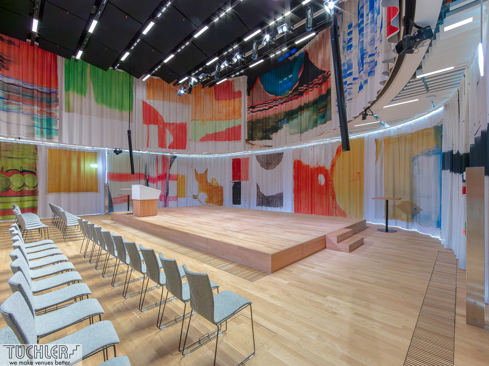 Architektur, Akustik und Kunst vereint: Digital bedruckte Kunstvorhänge mit TT2‑Schiene und T‑LOK‑Antrieb im Neubau in B